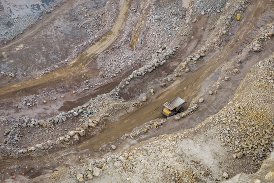 Aerial view of the Porphyry and Diabase Mine featuring a large haul truck driving along a dirt road within the rocky quarry landscape of Krakow, Lesser Poland Voivode, Poland.