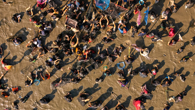 Aerial view of people fishing with nets and baskets in a muddy area in Kalikotes, Central Java, Indonesia.
