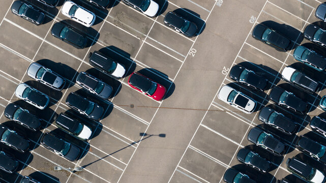 Aerial view of the JLR National Distribution Centre parking lot filled with numerous parked vehicles, including a red car, in Baxterley, England, United Kingdom.