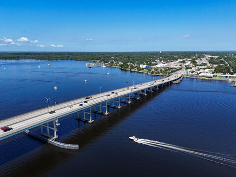 Boat passing under the Memorial Bridge on the St Johns River with historic downtown Palatka in the background in Putnam County, Florida. 