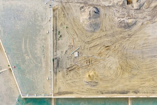 Aerial view of a residential development construction site with sandy ground, tire tracks, and construction materials in Perth, Western Australia, Australia.