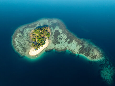Aerial view of Pass Island surrounded by turquoise coral reefs and deep blue sea in Coron, Philippines.