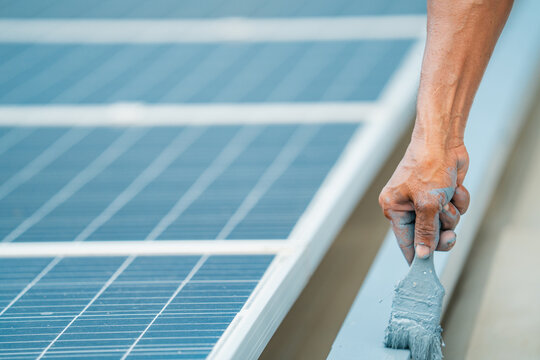 Solar electricity power technology for sustainable energy, solar panel hand paintbrush maintenance cleaning renewable energy worker roof blue repair