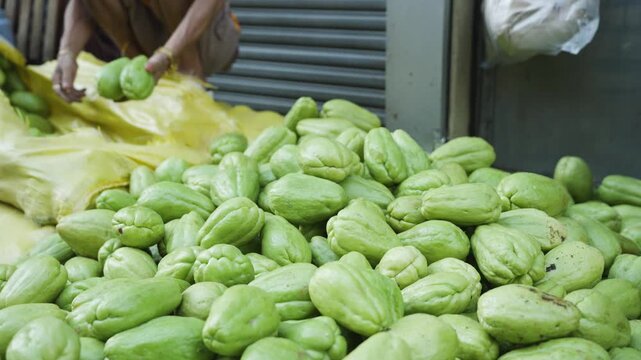 Vendor Removing and Arranging Chayote from a Sack at a Local Market