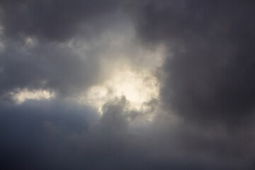 Obraz premium Dramatic Storm Clouds with Bright Sunlight Breaking Through, Dark Moody Sky and Atmospheric Weather Background