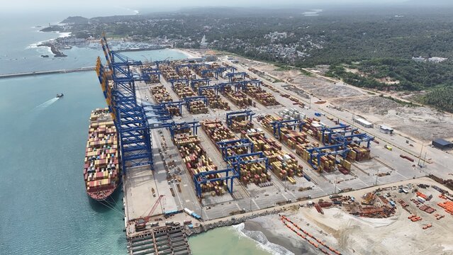 Thiruvananthapuram, India - 20 July 2026: Aerial view of Vizhinjam International Seaport Ltd featuring large container ships, rows of stacked shipping containers, and massive gantry cranes.