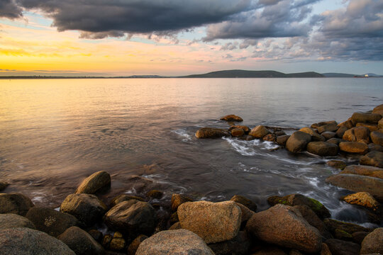 View of Middleton Beach at sunset with calm water, rocky shoreline, and dramatic clouds in the sky, Middleton Beach, Western Australia, Australia.