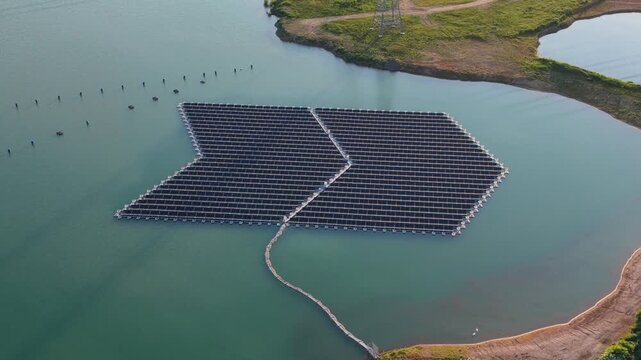 Aerial view of the floating solar park on a lake, featuring rows of solar panels on a pontoon system, surrounded by calm water and green banks in Bensheim, Hessen, Germany.