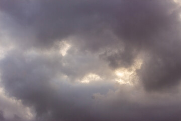 Obraz premium Dark Cloudy Sky with Sunlight Breaking Through Storm Clouds, Moody Weather and Dramatic Nature Background