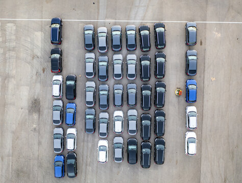 Aerial view of a car lot with rows of parked vehicles in various colors arranged on a paved surface in Ramat Hasharon, Tel Aviv District, Israel.
