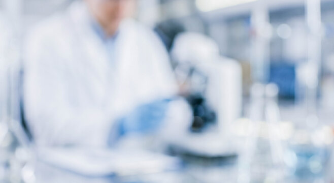 A blurred scene of a scientist working in a laboratory, showing equipment like a microscope and glassware, highlighting scientific research activity.