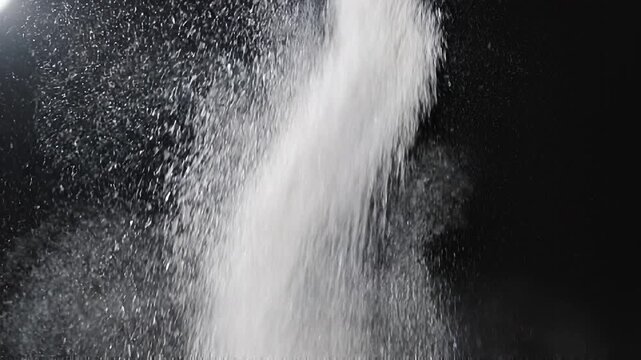White powdered sugar falling against a dark background
