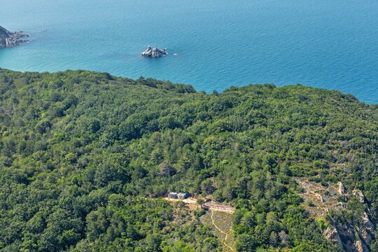 Aerial view of a small structure and rows of beehives nestled within a dense forest and blue waters near Kiyikoy, Kirklareli, Turkey.