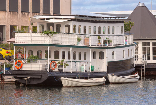 Traditional houseboat with small boats in Copenhagen harbor Denmark
