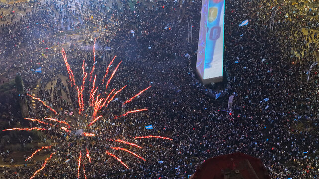 Buenos Aires, Argentina - 19 July 2026: Aerial view of a massive crowd celebrating at the Obelisco on Avenida 9 de Julio, illuminated by fireworks and vibrant night city lights.