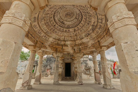 View of Ancient Gori Temple with its intricately carved stone columns and a detailed circular ceiling dome featuring historic murals in Guri, Sindh, Pakistan.