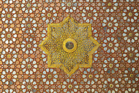 View of the intricate geometric ceiling pattern with gold filigree and mirror work at the shrine of Peer Mahmood Hassan Qureshi in Kaamaro Sharif, Sindh, Pakistan.