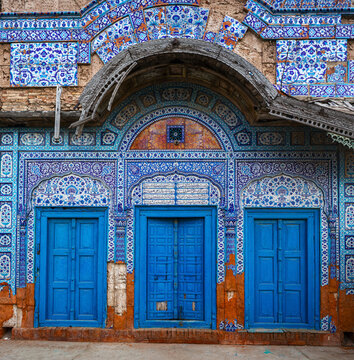 View of the ornate blue and white tile work and three vibrant blue wooden doors at the historic Shrine of Peer Mahmood Hassan Qureshi in Kaamaro Sharif, Sindh, Pakistan.
