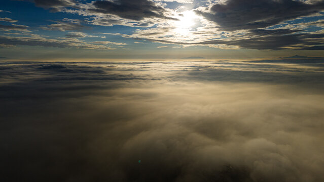 Aerial view of Akyokus hill covered in a thick layer of clouds during sunset with golden light reflecting on the mist in Meram, Konya, Turkiye.