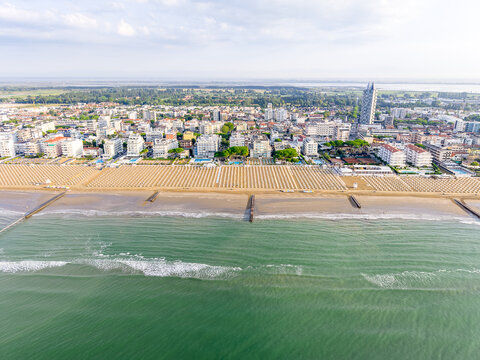 Aerial view of the sandy beach with rows of umbrellas and the coastal town skyline in Lido di Jesolo, Veneto, Italy.