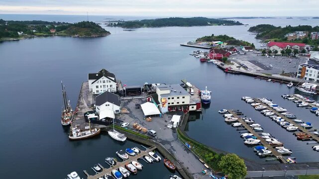 Aerial view of the harbor in Grimstad with boats docked at the marina and surrounding coastal landscape in Grimstad, Agder, Norway.