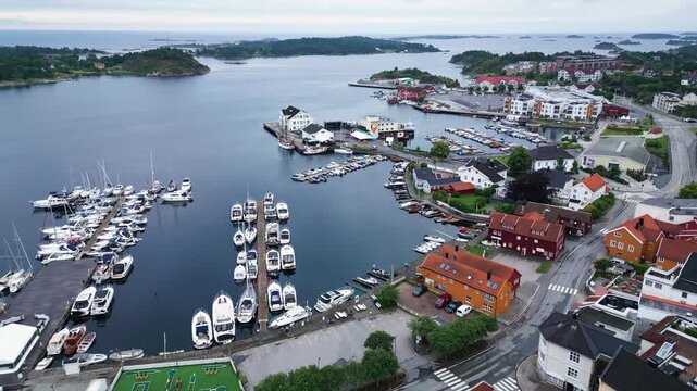 Aerial view of the marina in Grimstad with numerous boats docked, surrounded by colorful houses and coastal landscape in Grimstad, Agder, Norway.