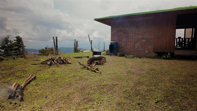 outdoor cooking setup with pots on an open fire next to a rustic house