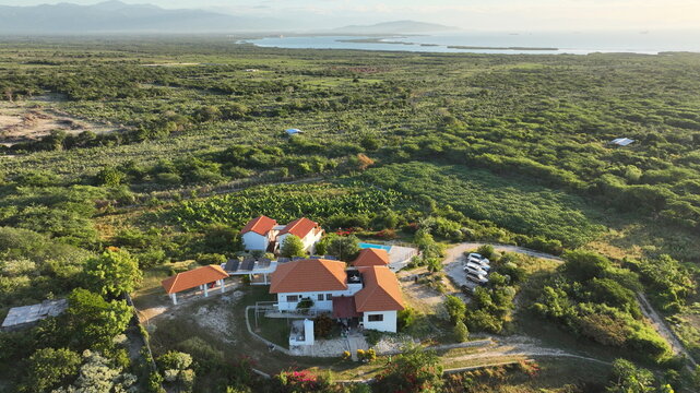 Aerial view of Altos de La Caobita Eco-hotel with terracotta roofs, swimming pool, and solar panels, set in lush coastal vegetation in Barrera, Azua, Dominican Republic.