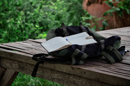 Open Travel Journal and Backpack on Wooden Table in Nature