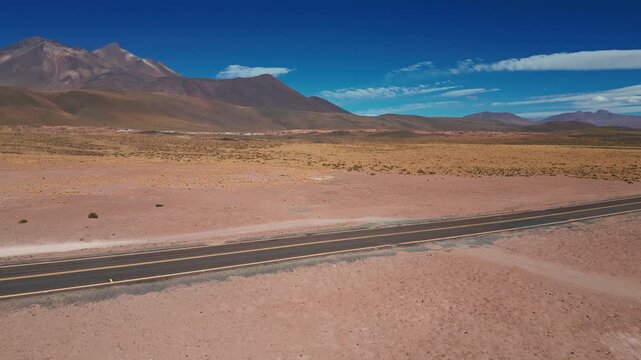 Aerial view of a desert landscape with a road and rheas roaming in the arid terrain in Antofagasta, Antofagasta, Chile.