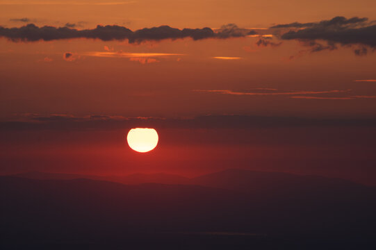 Aerial view of the sunset from Maly Milic with vibrant orange and red hues illuminating the horizon over the rolling hills of Skaros, Kosice Region, Slovakia.