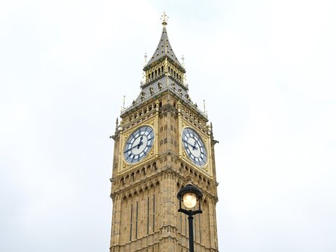 View of the Elizabeth Tower, commonly known as Big Ben, featuring its intricate gothic architecture and clock faces against a bright sky in London, England, United Kingdom.