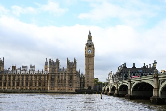 View of the iconic Big Ben clock tower and the historic Palace of Westminster rising above the River Thames under a cloudy sky in London, England, United Kingdom.