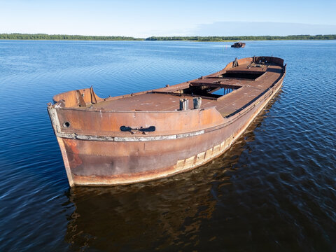 Aerial view of a rusted, abandoned barge floating in the calm blue waters of Pateniemenranta in Oulu, Pohjois-Pohjanmaa, Finland.