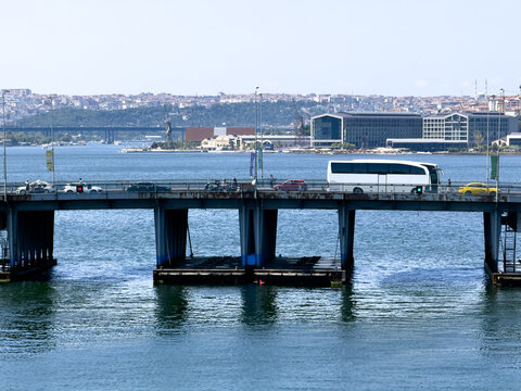 View of the Ataturk Bridge crossing the Golden Horn with traffic including a white bus and cars, with the urban skyline of the city in the background in Fatih, Istanbul, Turkiye.