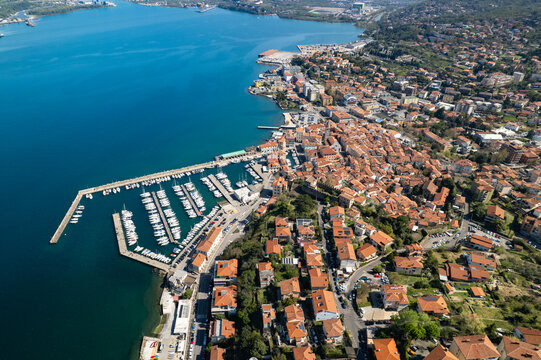 Aerial view of the historic town of Muggia with its marina, colorful rooftops, and coastal architecture in Trieste, Friuli-Venezia Giulia, Italy.