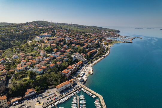 Aerial view of Muggia with its historic harbor, colorful buildings, and boats docked along the waterfront in Trieste, Friuli-Venezia Giulia, Italy.