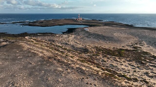 Aerial view of Faro del Toston lighthouse surrounded by rocky coastal terrain and the Atlantic Ocean in Canary Islands, Spain.
