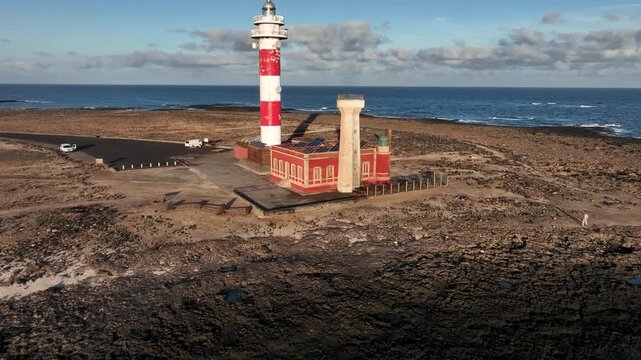 Aerial view of the iconic Faro de Toston lighthouse situated on the rugged volcanic coastline of Fuerteventura in La Oliva, Canary Islands, Spain.