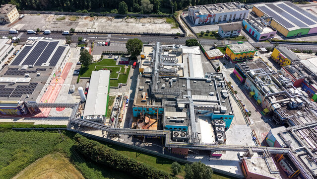 Aerial view of a pharmaceutical industrial cluster featuring modern production facilities, research infrastructure, and complex piping systems in Milan, Lombardy, Italy.