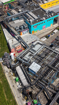 Aerial view of a pharmaceutical industrial cluster featuring modern production facilities, complex piping networks, and research infrastructure in Milan, Lombardy, Italy.