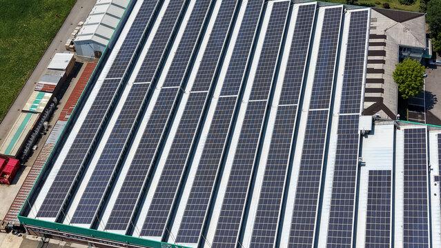 Milan, Italy - 19 June 2026: Aerial view of an industrial facility rooftop covered in extensive solar panel arrays, highlighting sustainable energy integration for HVAC systems.