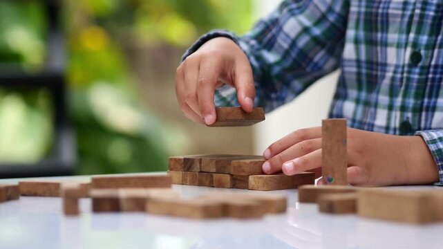 kid playing with wooden bricks. Children constructing house from colored elements. Bright toy building - real estate theme.