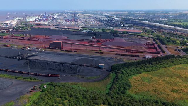 Aerial view of Immingham Bulk Terminal with large stockpiles of iron ore and coal, conveyor systems, and industrial infrastructure in South Killingholme, England, United Kingdom.