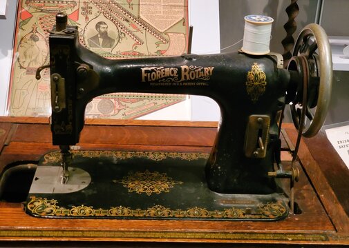 Pittsburgh, Pennsylvania, U.S.A - Jul 18, 2026 - An antique Florence Rotary sewing machine with ornate gold detailing and vintage poster backdrop.