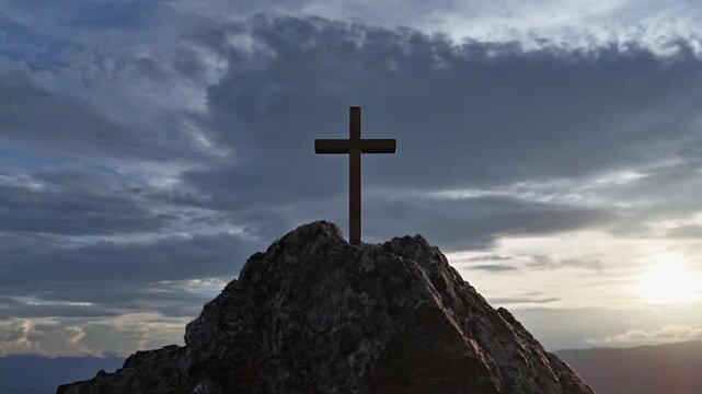 Silhouettes of crucifix symbol on top mountain with bright sunbeam on the colorful sky background	