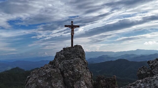 Silhouettes of crucifix symbol on top mountain with bright sunbeam on the colorful sky background	