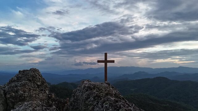 Silhouettes of crucifix symbol on top mountain with bright sunbeam on the colorful sky background	