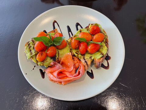 Toasted artisanal sourdough topped with smashed avocado, premium smoked salmon, and blistered cherry tomatoes