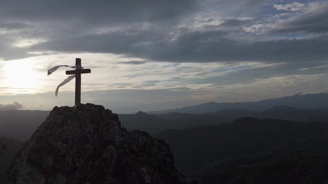 Silhouettes of crucifix symbol on top mountain with bright sunbeam on the colorful sky background	